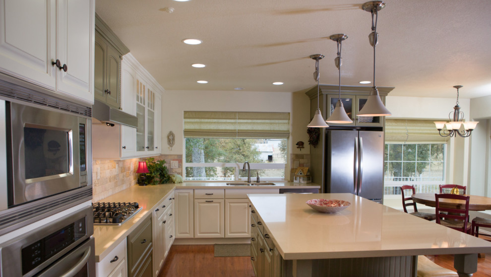 Inspiration for a mid-sized transitional l-shaped medium tone wood floor open concept kitchen remodel with a double-bowl sink, raised-panel cabinets, white cabinets, white backsplash, stainless steel appliances and an island