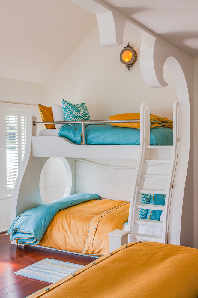 Photo of a beach style gender-neutral kids' bedroom in Other with white walls, medium hardwood floors and brown floor.