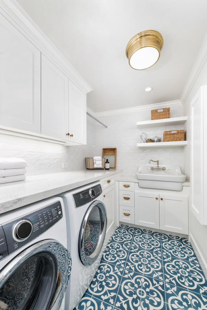 This is an example of a small country l-shaped dedicated laundry room in San Francisco with a farmhouse sink, white cabinets, quartz benchtops, white walls, ceramic floors, a side-by-side washer and dryer, blue floor, white benchtop and shaker cabinets.
