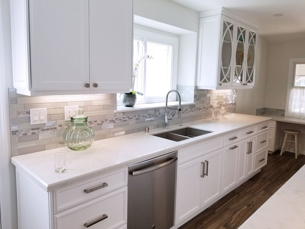 Design ideas for a small traditional galley separate kitchen in Los Angeles with an undermount sink, glass-front cabinets, white cabinets, quartz benchtops, grey splashback, glass tile splashback, stainless steel appliances, porcelain floors, no island and brown floor.