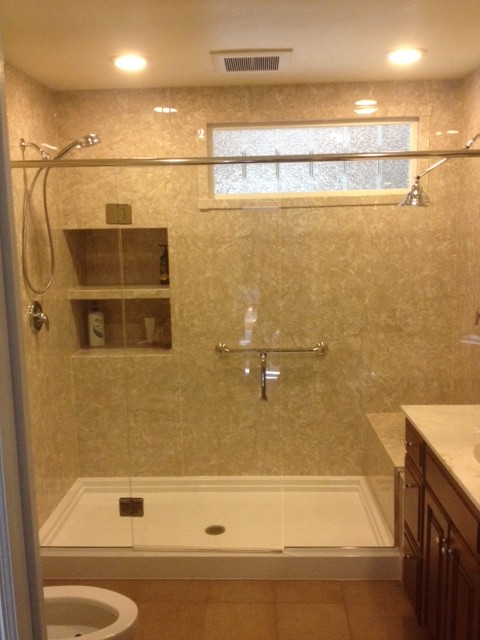 This is an example of a mid-sized traditional 3/4 bathroom in Philadelphia with raised-panel cabinets, brown cabinets, an alcove shower, gray tile, stone slab, porcelain floors, marble benchtops and a hinged shower door.