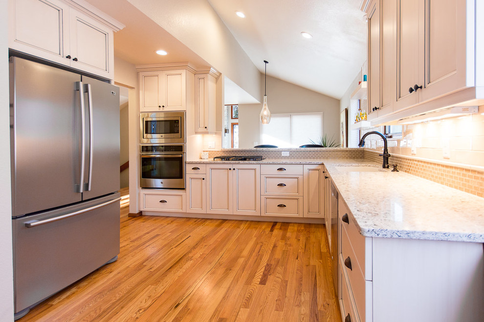 Eat-in kitchen - transitional light wood floor and brown floor eat-in kitchen idea with an undermount sink, shaker cabinets, white cabinets, quartz countertops, white backsplash, ceramic backsplash and stainless steel appliances