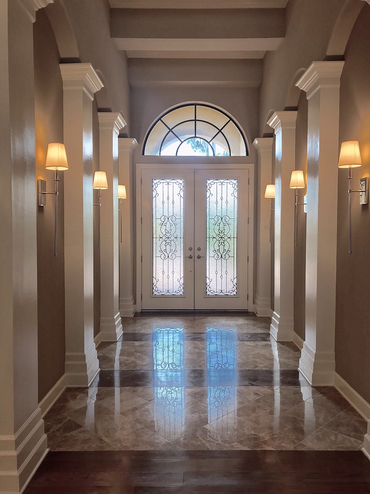 Double front door - mid-sized transitional limestone floor and multicolored floor double front door idea in Tampa with brown walls and a glass front door