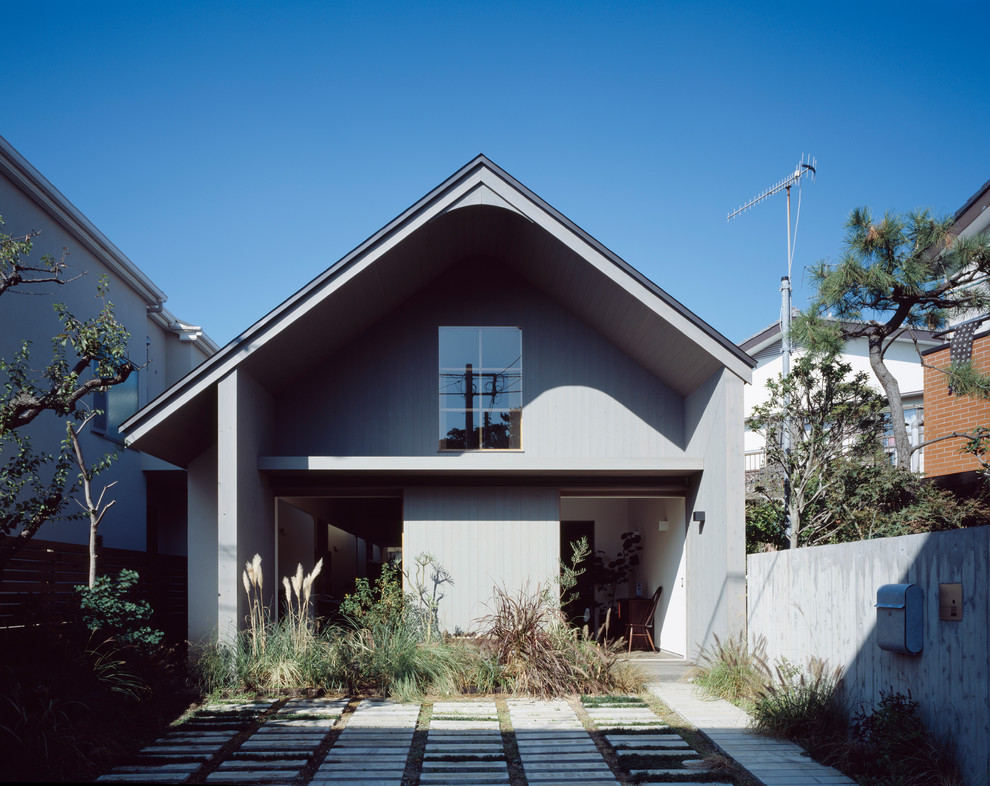 Photo of a modern two-storey grey house exterior in Yokohama with wood siding, a gable roof and a metal roof.