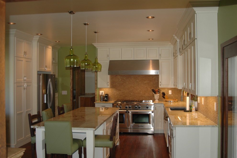 Design ideas for a mid-sized traditional u-shaped kitchen in Orlando with an undermount sink, shaker cabinets, yellow cabinets, granite benchtops, beige splashback, glass tile splashback, stainless steel appliances, medium hardwood floors, with island and brown floor.
