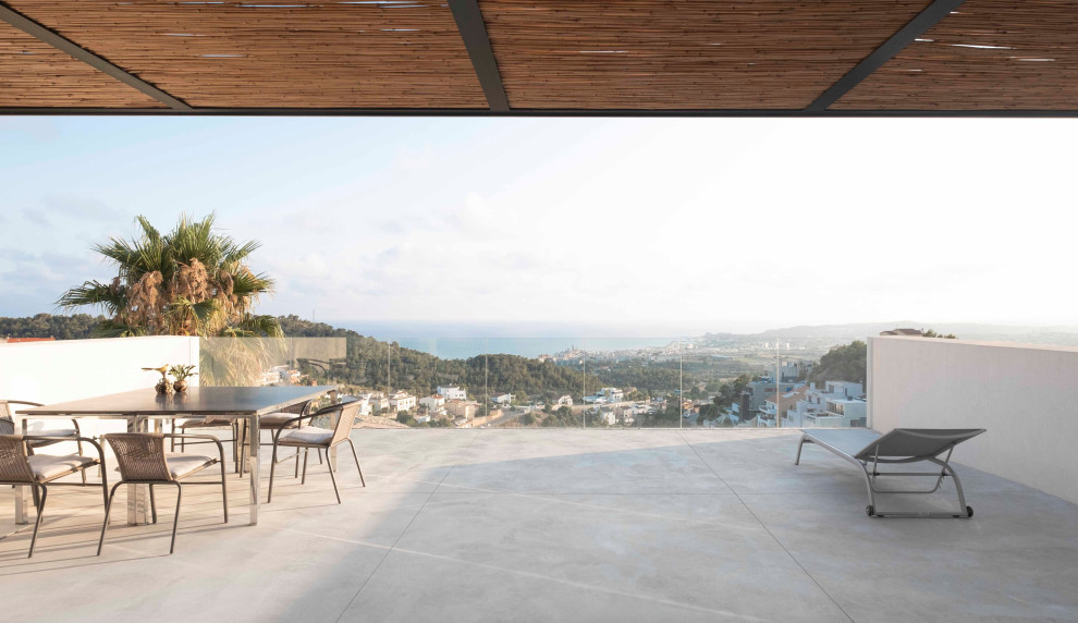 Cette photo montre une terrasse sur le toit moderne avec des solutions pour vis-à-vis, aucune couverture et un garde-corps en verre.