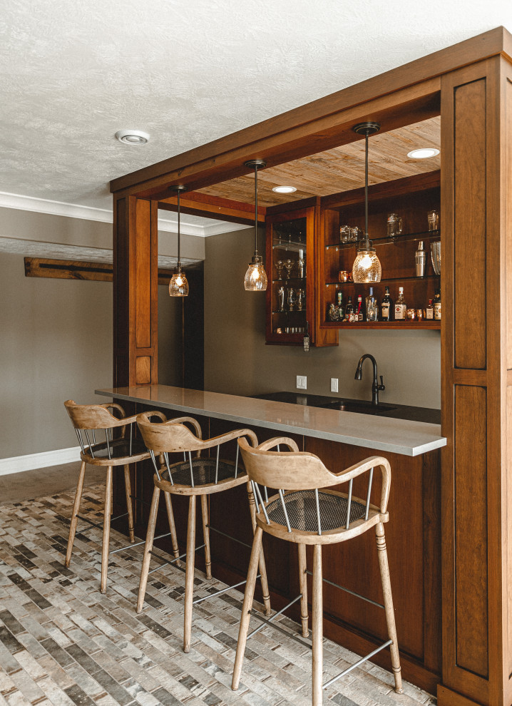 Design ideas for a mid-sized country galley seated home bar in Other with an undermount sink, flat-panel cabinets, medium wood cabinets, quartz benchtops, brick floors, beige floor and grey benchtop.
