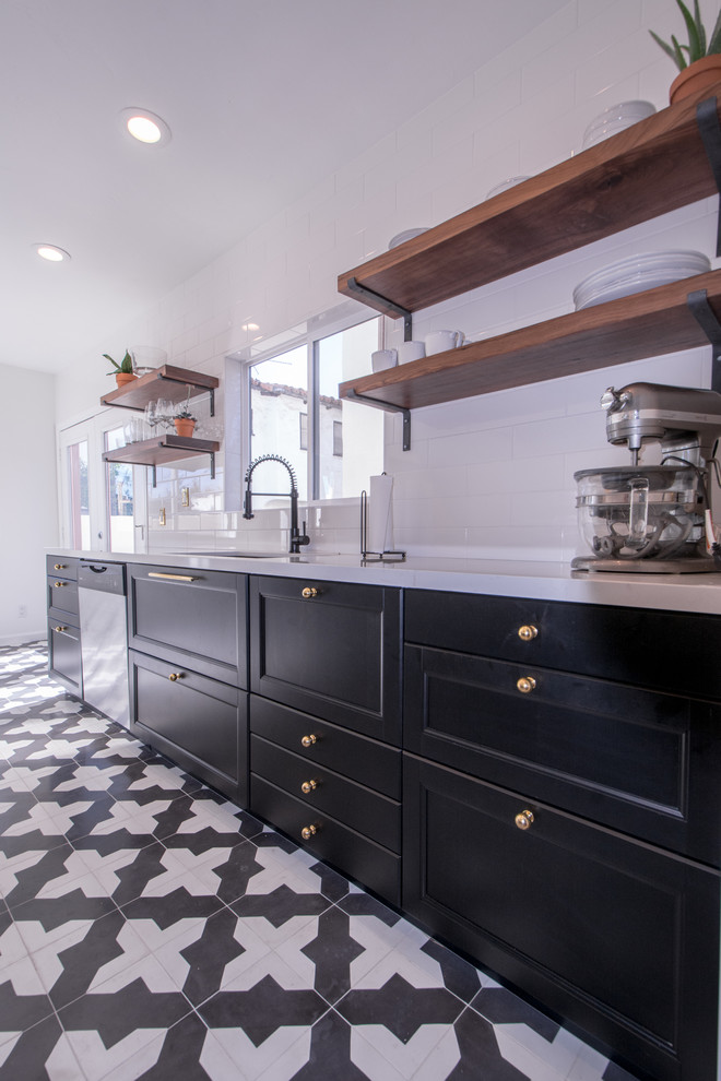 Design ideas for a mid-sized modern open plan kitchen in San Diego with an undermount sink, shaker cabinets, black cabinets, solid surface benchtops, white splashback, subway tile splashback, stainless steel appliances and porcelain floors.