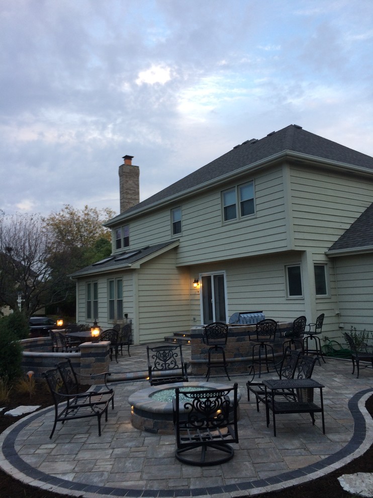 Mid-sized transitional backyard stone patio photo in Chicago with a fire pit and no cover