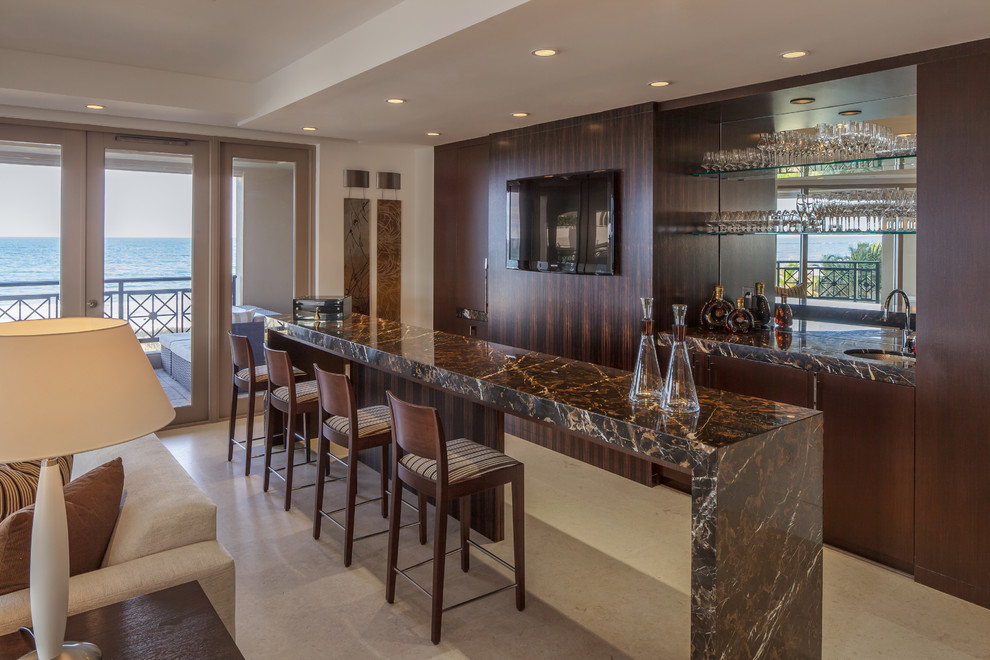 Photo of a large contemporary single-wall wet bar in Miami with flat-panel cabinets, dark wood cabinets, marble benchtops, limestone floors, an undermount sink and mirror splashback.