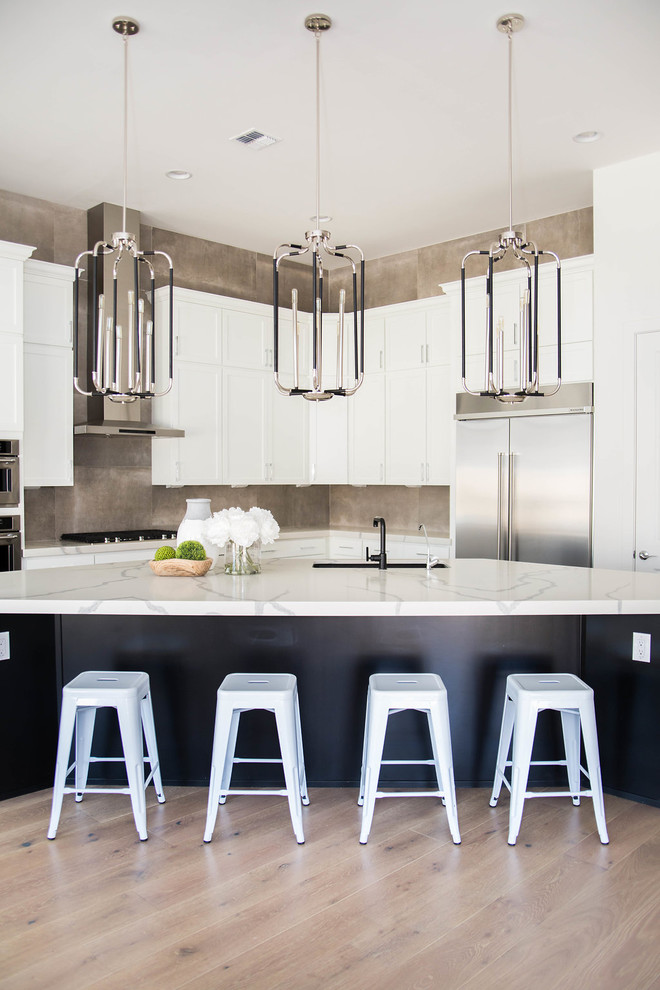 Example of a large transitional light wood floor and yellow floor open concept kitchen design in Phoenix with a single-bowl sink, shaker cabinets, white cabinets, quartz countertops, gray backsplash, cement tile backsplash, stainless steel appliances, an island and white countertops