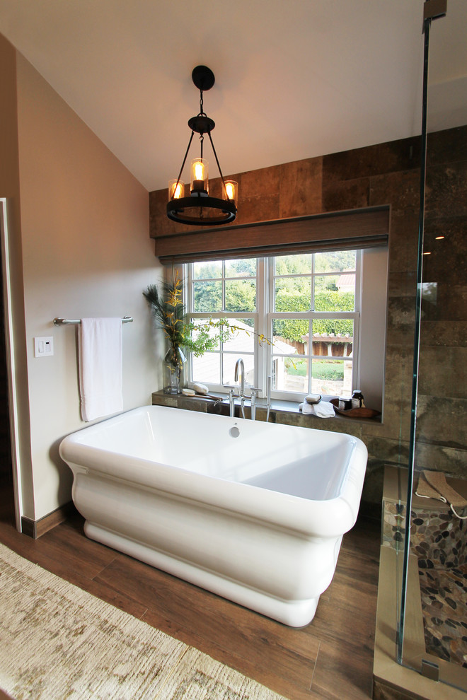 Inspiration for a large country master bathroom in Los Angeles with raised-panel cabinets, dark wood cabinets, a freestanding tub, a corner shower, a bidet, brown tile, stone tile, beige walls, porcelain floors, an undermount sink, quartzite benchtops, brown floor and a hinged shower door.