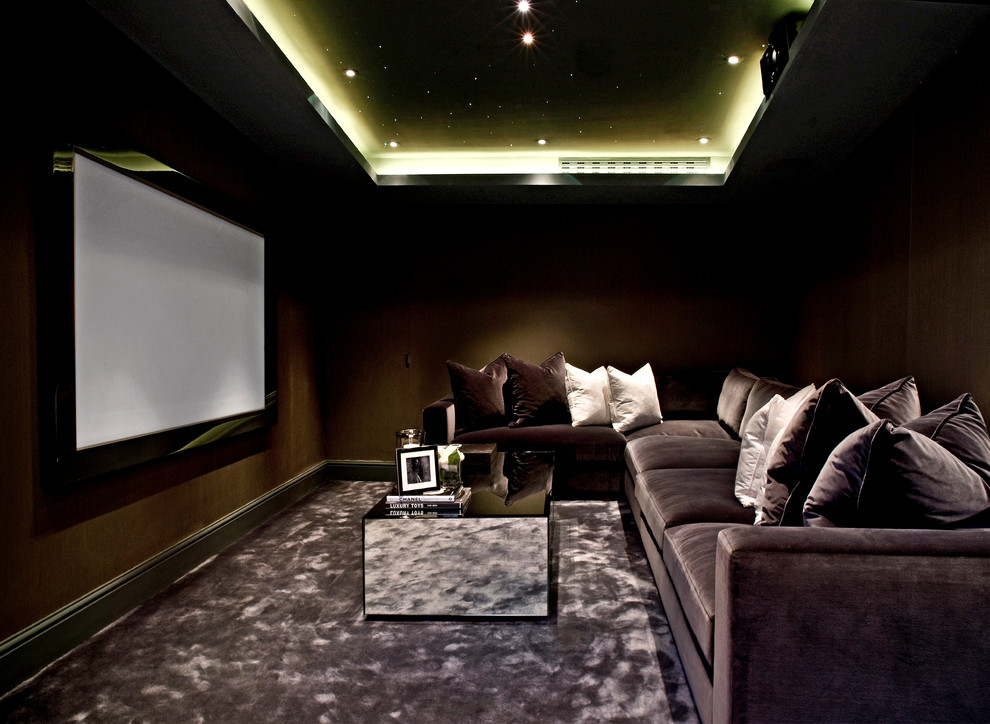 This is an example of a contemporary enclosed home theatre in London with brown walls, carpet, a projector screen and grey floor.
