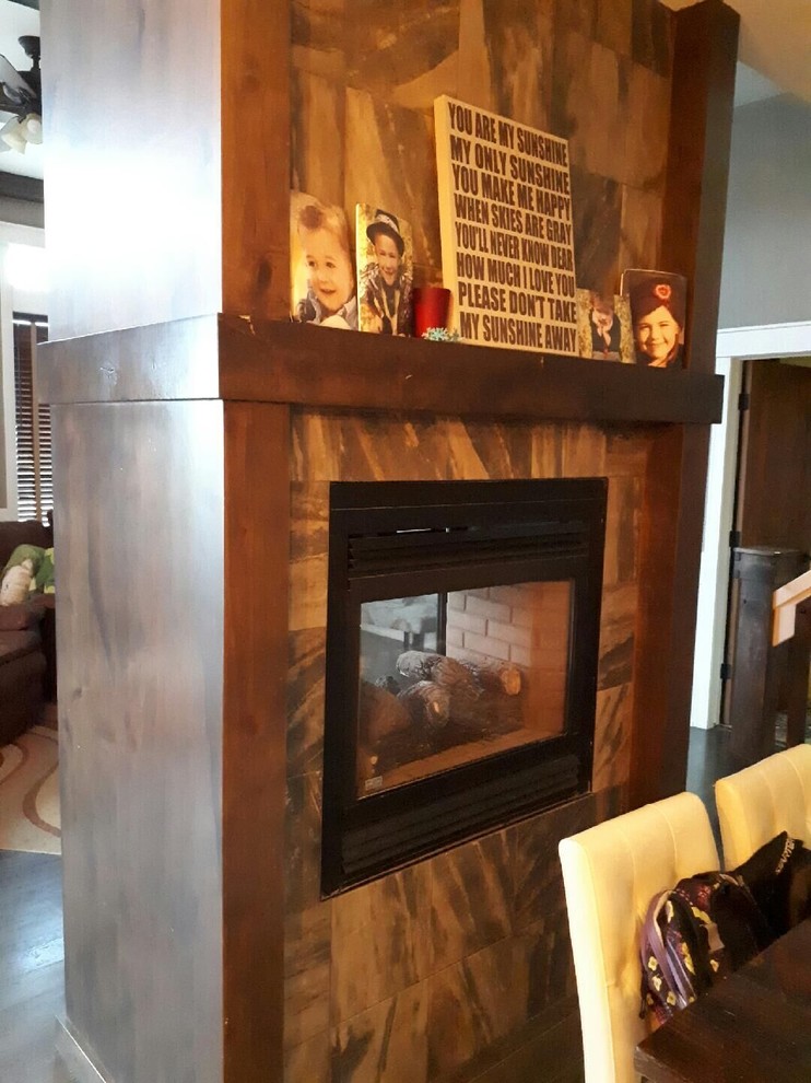 Kitchen/dining room combo - mid-sized transitional medium tone wood floor and brown floor kitchen/dining room combo idea in Calgary with gray walls, a two-sided fireplace and a tile fireplace