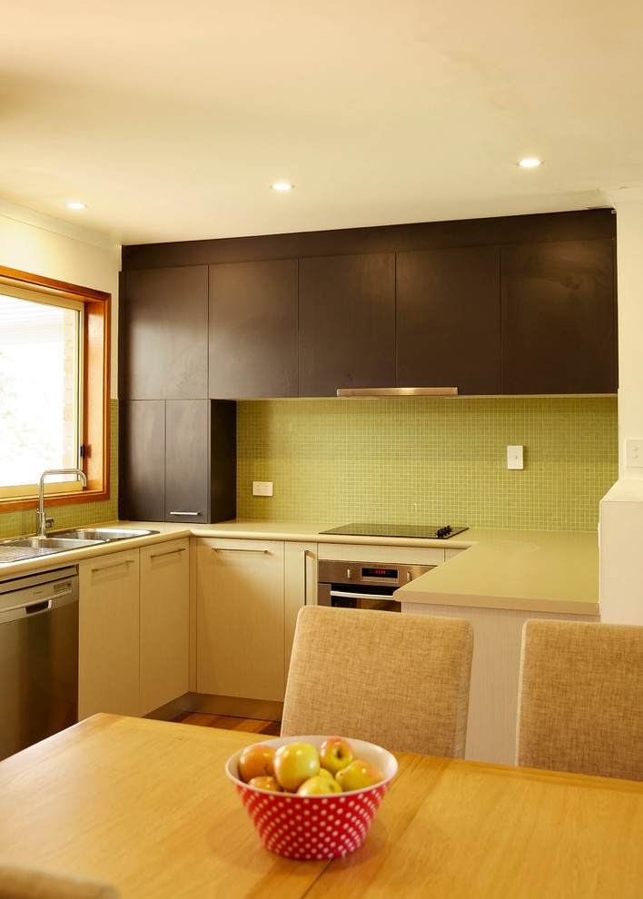 Inspiration for a small modern u-shaped eat-in kitchen in Canberra - Queanbeyan with a double-bowl sink, laminate benchtops, green splashback, glass tile splashback, stainless steel appliances and medium hardwood floors.