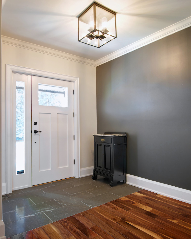This is an example of a mid-sized arts and crafts foyer in Toronto with grey walls, limestone floors, a single front door and a white front door.