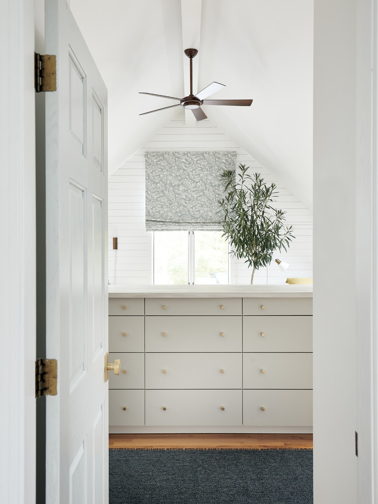 Large beach style gender-neutral walk-in wardrobe in Boston with flat-panel cabinets, grey cabinets, light hardwood floors and brown floor.