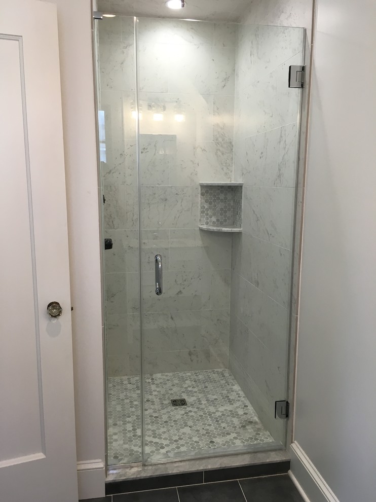 Photo of a mid-sized traditional master bathroom in Newark with recessed-panel cabinets, grey cabinets, an alcove shower, a one-piece toilet, gray tile, white tile, porcelain tile, white walls, ceramic floors and marble benchtops.