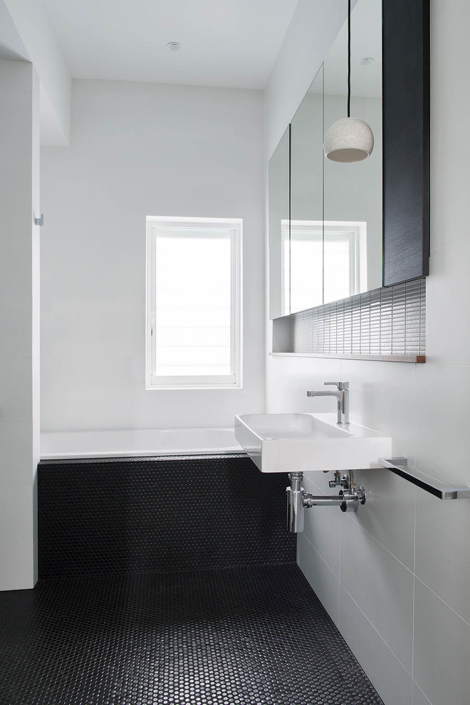 Contemporary bathroom in Perth with a drop-in tub, white tile, white walls, mosaic tile floors, a wall-mount sink and black floor.