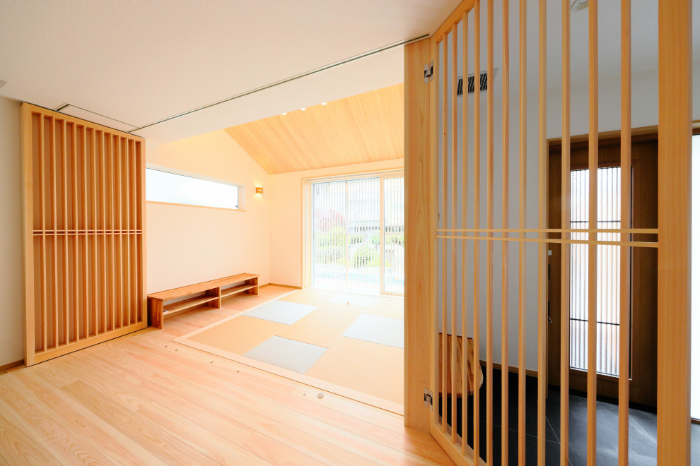 Inspiration for a traditional entryway in Nagoya with white walls, light hardwood floors, a sliding front door and a light wood front door.