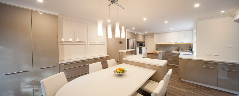 Photo of an expansive contemporary u-shaped eat-in kitchen in Sydney with an undermount sink, flat-panel cabinets, green cabinets, quartz benchtops, brown splashback, glass sheet splashback, stainless steel appliances, ceramic floors and multiple islands.