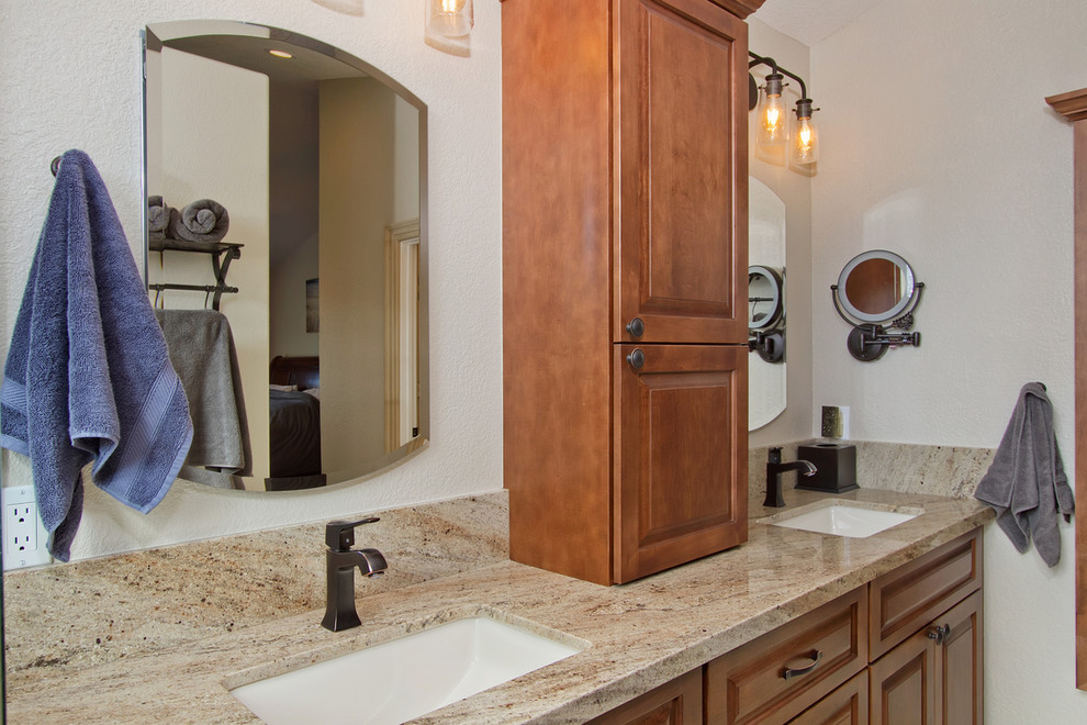 Photo of a large traditional master bathroom in San Diego with recessed-panel cabinets, medium wood cabinets, a corner shower, a two-piece toilet, beige tile, travertine, yellow walls, porcelain floors, beige floor, a hinged shower door, an undermount sink, engineered quartz benchtops, beige benchtops, a double vanity and a built-in vanity.