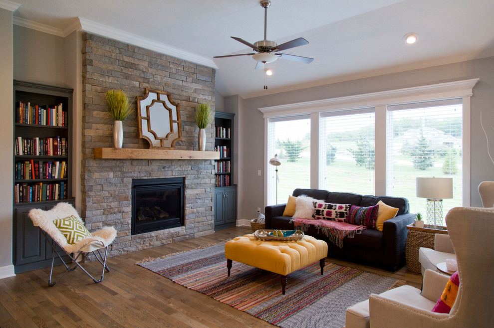 Photo of a large traditional open concept living room in Kansas City with medium hardwood floors, a standard fireplace, a stone fireplace surround, brown floor and grey walls.