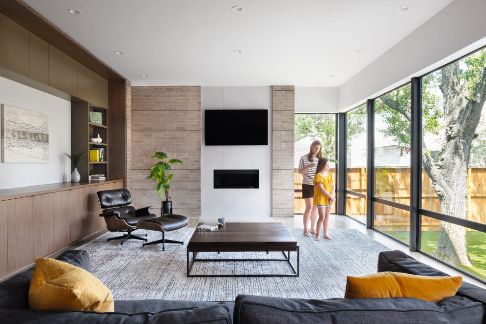 Mid-sized contemporary open concept living room in Houston with white walls, light hardwood floors, a ribbon fireplace, a tile fireplace surround, a wall-mounted tv, brown floor and brick walls.