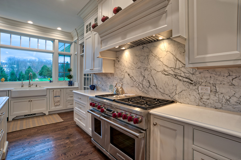 Large elegant u-shaped medium tone wood floor and brown floor eat-in kitchen photo in Philadelphia with a farmhouse sink, beaded inset cabinets, white cabinets, quartz countertops, white backsplash, quartz backsplash, stainless steel appliances, an island and white countertops