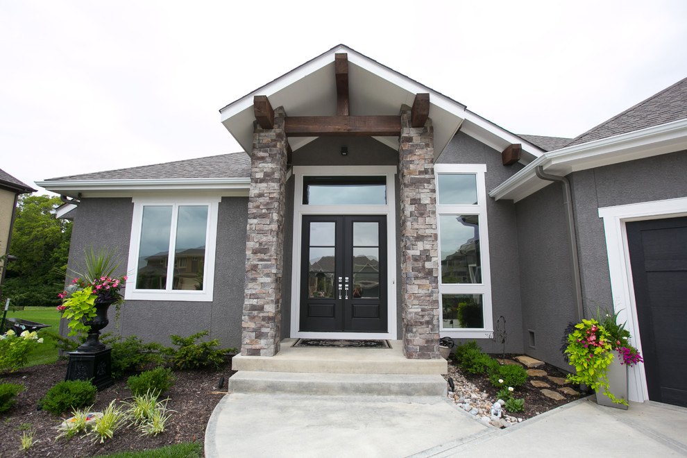This is an example of a mid-sized transitional one-storey adobe grey exterior in Kansas City with a gable roof.