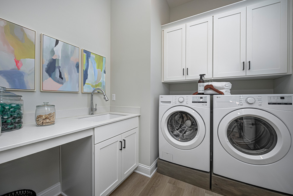Exempel på en mellanstor klassisk vita linjär vitt tvättstuga enbart för tvätt, med en undermonterad diskho, skåp i shakerstil, vita skåp, bänkskiva i kvarts, grå väggar, mellanmörkt trägolv, en tvättmaskin och torktumlare bredvid varandra och brunt golv