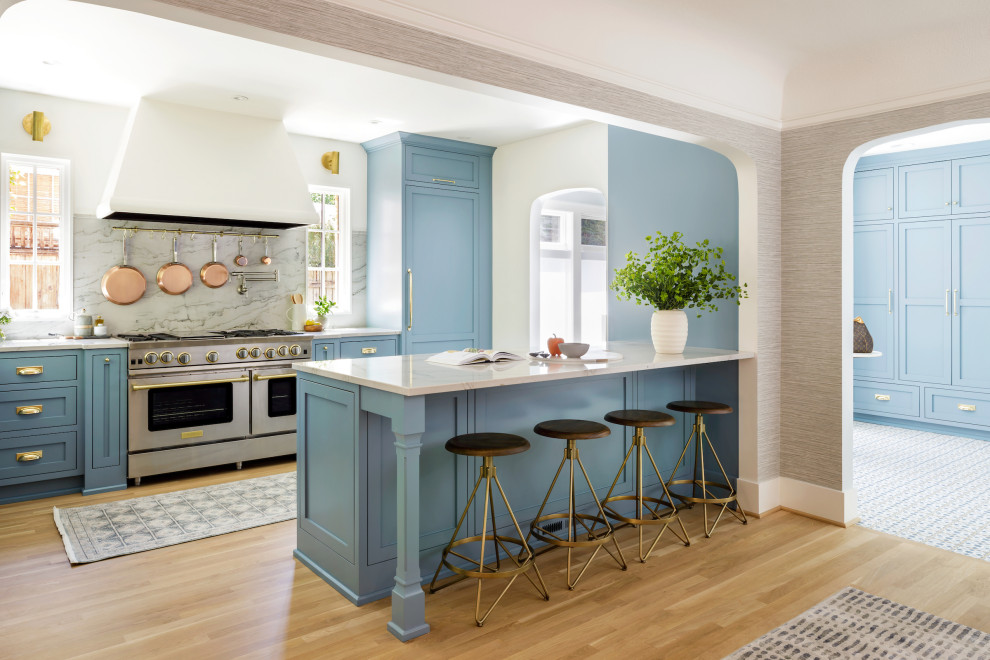 Medium sized traditional galley kitchen/diner in Portland with a submerged sink, recessed-panel cabinets, blue cabinets, quartz worktops, stone slab splashback, integrated appliances, light hardwood flooring and a breakfast bar.