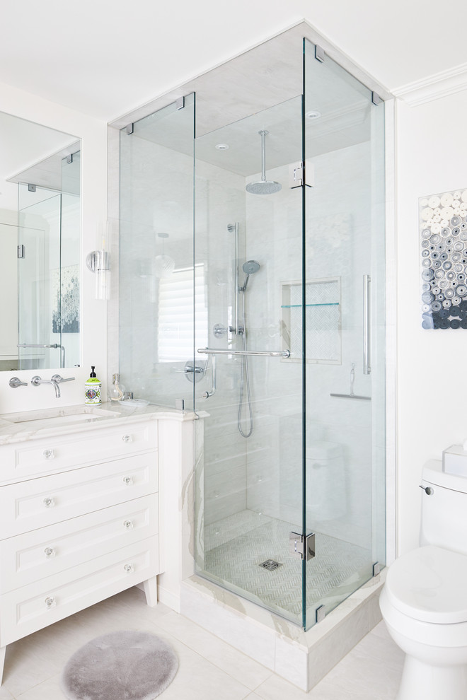 Photo of a large contemporary master bathroom in Toronto with furniture-like cabinets, white cabinets, a freestanding tub, a corner shower, white tile, porcelain tile, grey walls, porcelain floors, an undermount sink, engineered quartz benchtops, white floor, a hinged shower door, white benchtops and a one-piece toilet.
