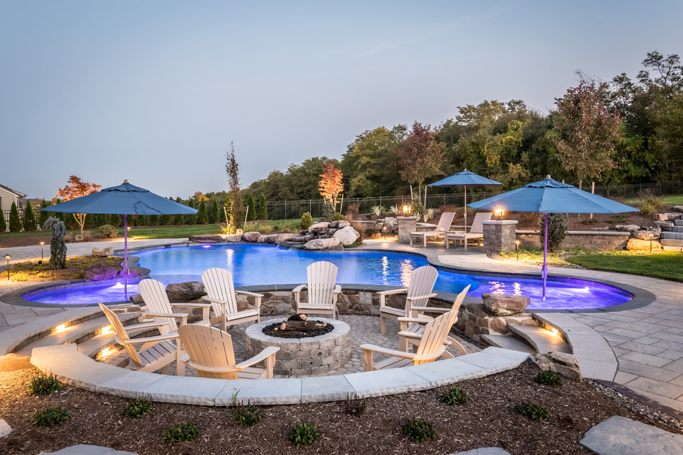 Inspiration for a large transitional backyard concrete paver and custom-shaped pool remodel