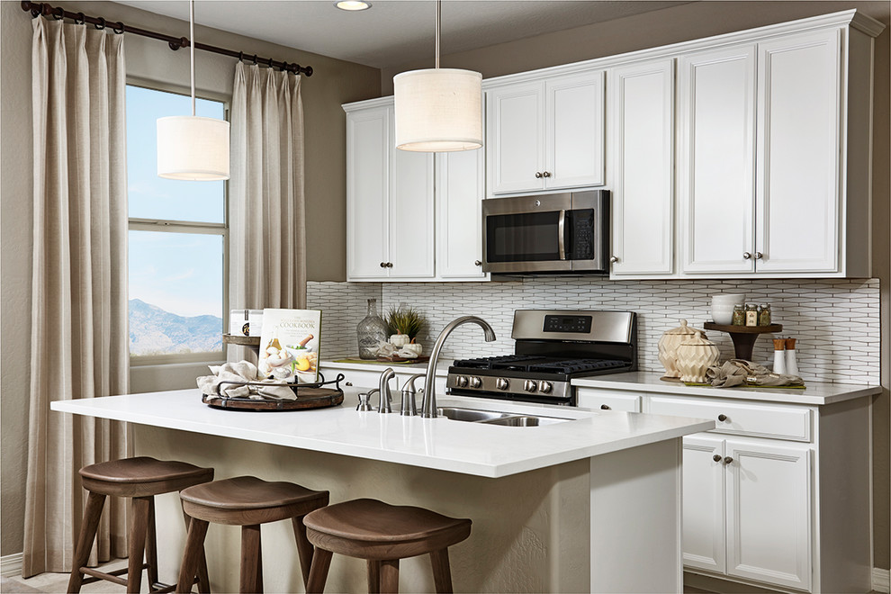 Design ideas for a contemporary kitchen in Denver with white cabinets, white splashback, stainless steel appliances, with island and white benchtop.