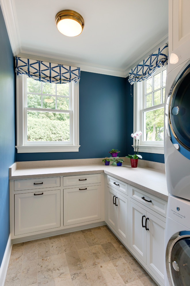Inspiration for a mid-sized traditional l-shaped dedicated laundry room in Minneapolis with white cabinets, concrete benchtops, blue walls, porcelain floors, a stacked washer and dryer, beige floor, beige benchtop and recessed-panel cabinets.