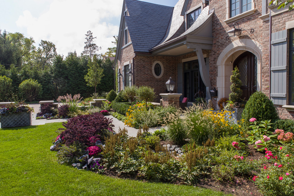 Large traditional front yard partial sun formal garden in Chicago with a garden path and natural stone pavers.