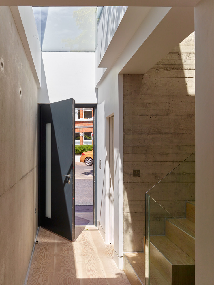 Inspiration for a modern foyer in London with grey walls, light hardwood floors, a single front door, a black front door and beige floor.
