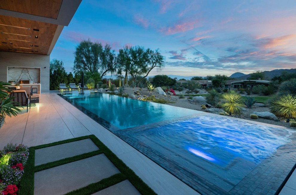 Diseño de piscina infinita moderna extra grande rectangular en patio trasero con paisajismo de piscina y suelo de baldosas