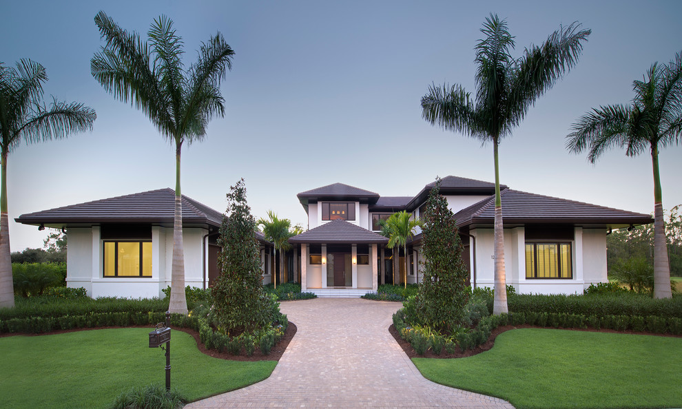Design ideas for a tropical two-storey stucco white exterior in Miami with a hip roof and a tile roof.