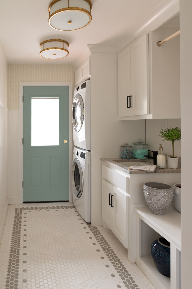 Galley dedicated laundry room in Kansas City with a drop-in sink, recessed-panel cabinets, white cabinets, marble benchtops, white walls, porcelain floors, a stacked washer and dryer, multi-coloured floor and multi-coloured benchtop.