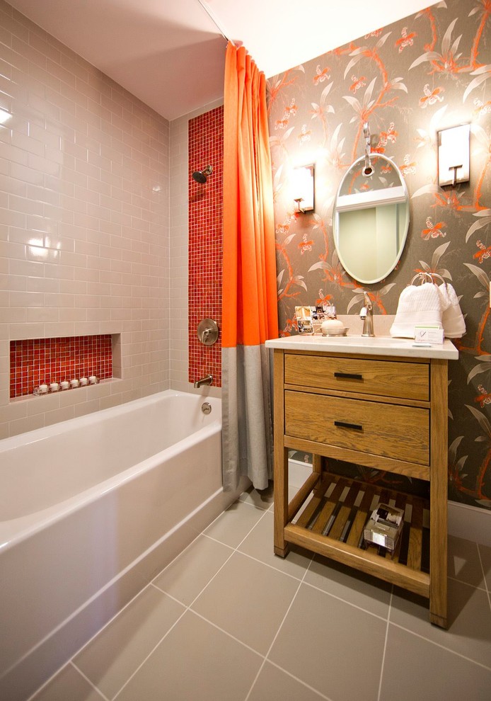 This is an example of a transitional bathroom in Portland Maine with furniture-like cabinets, medium wood cabinets, a freestanding tub, a shower/bathtub combo, a two-piece toilet, orange tile, glass tile, porcelain floors, an integrated sink, engineered quartz benchtops, grey floor, a shower curtain, white benchtops, a single vanity and wallpaper.