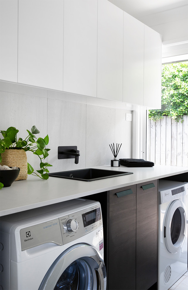 Photo of a beach style single-wall dedicated laundry room in Sunshine Coast with a drop-in sink, flat-panel cabinets, white cabinets, white walls, a side-by-side washer and dryer, white floor and white benchtop.