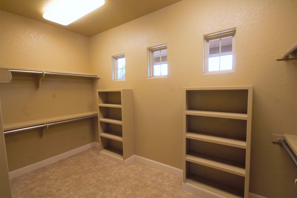 Large traditional gender-neutral walk-in wardrobe in Austin with open cabinets, beige cabinets, porcelain floors and beige floor.