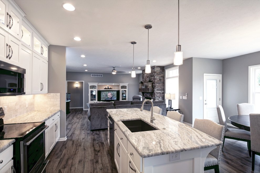 Inspiration for a transitional l-shaped gray floor eat-in kitchen remodel with an undermount sink, glass-front cabinets, white cabinets, beige backsplash, stone tile backsplash, stainless steel appliances, an island and multicolored countertops