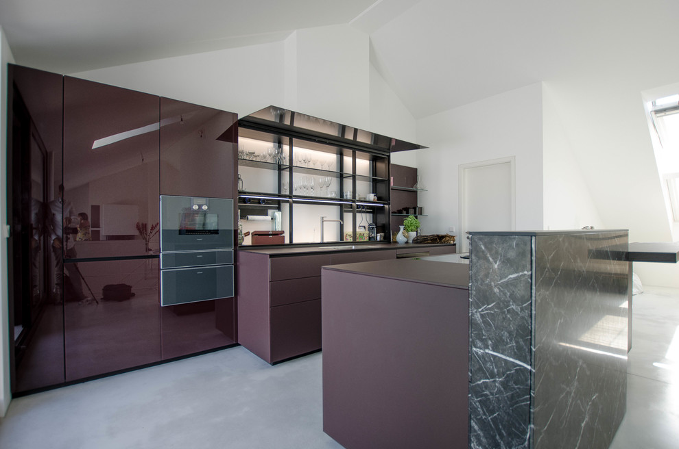 Photo of an expansive contemporary galley eat-in kitchen in Berlin with a single-bowl sink, glass-front cabinets, purple cabinets, glass benchtops, glass sheet splashback, black appliances, concrete floors, with island, grey floor and purple benchtop.