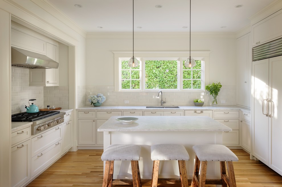 Inspiration for a mid-sized transitional u-shaped light wood floor kitchen remodel in Seattle with an undermount sink, shaker cabinets, white cabinets, quartzite countertops, green backsplash, ceramic backsplash, paneled appliances and an island