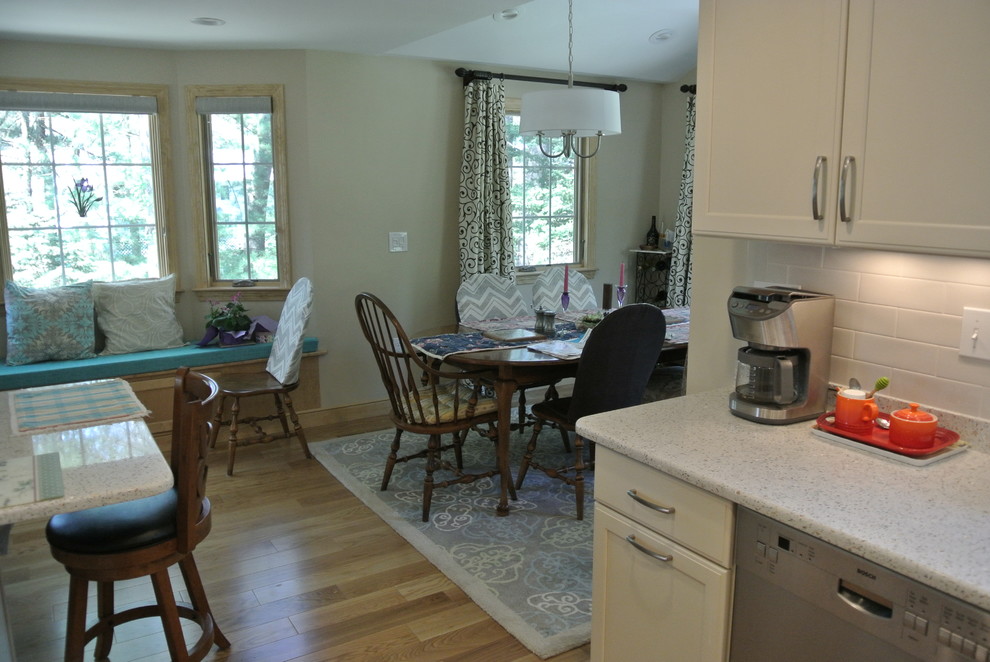 Inspiration for a transitional l-shaped medium tone wood floor eat-in kitchen remodel in Boston with an undermount sink, shaker cabinets, white cabinets, recycled glass countertops, white backsplash, subway tile backsplash, stainless steel appliances, a peninsula and white countertops