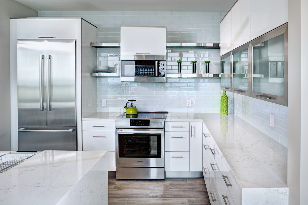 Example of a small trendy l-shaped porcelain tile and brown floor eat-in kitchen design in Sacramento with an undermount sink, flat-panel cabinets, white cabinets, quartz countertops, white backsplash, subway tile backsplash, stainless steel appliances, an island and white countertops