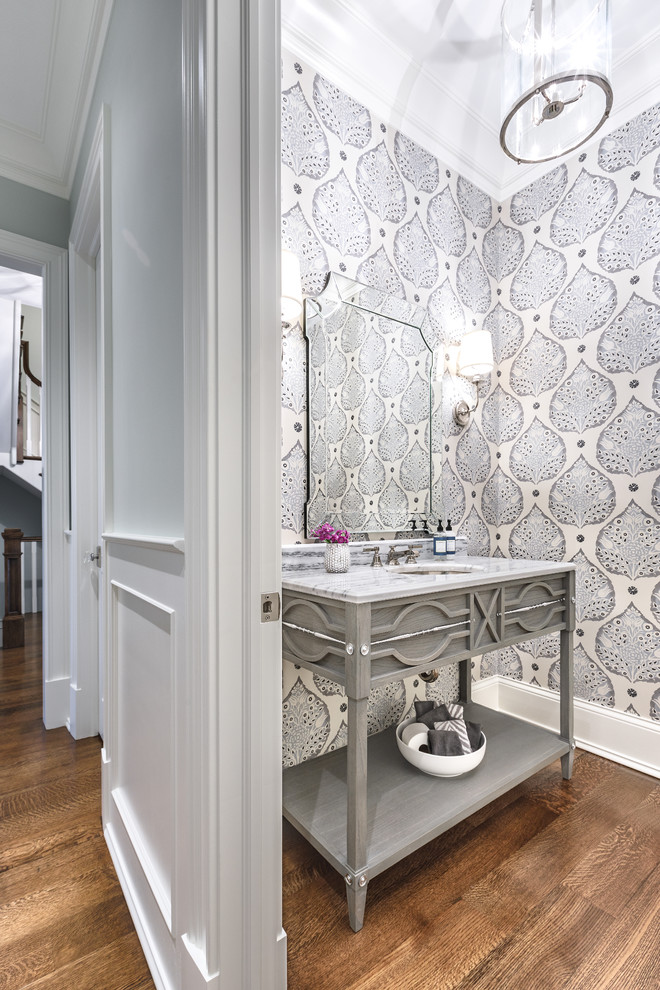This is an example of a mid-sized transitional powder room in Chicago with furniture-like cabinets, grey cabinets, medium hardwood floors, an undermount sink and white benchtops.